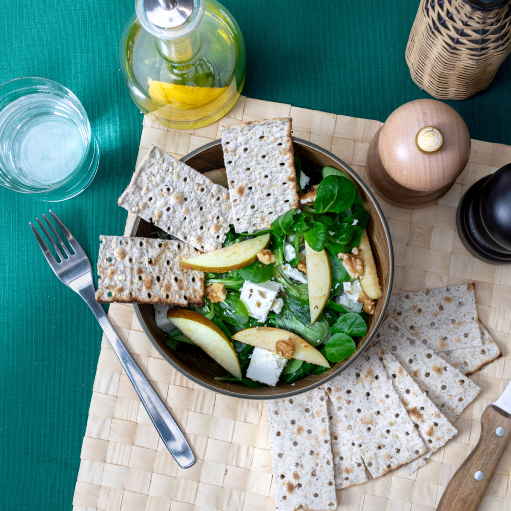 Salade composée avec mâche, pommes, feta, noix et morceaux de pain azyme Heumann