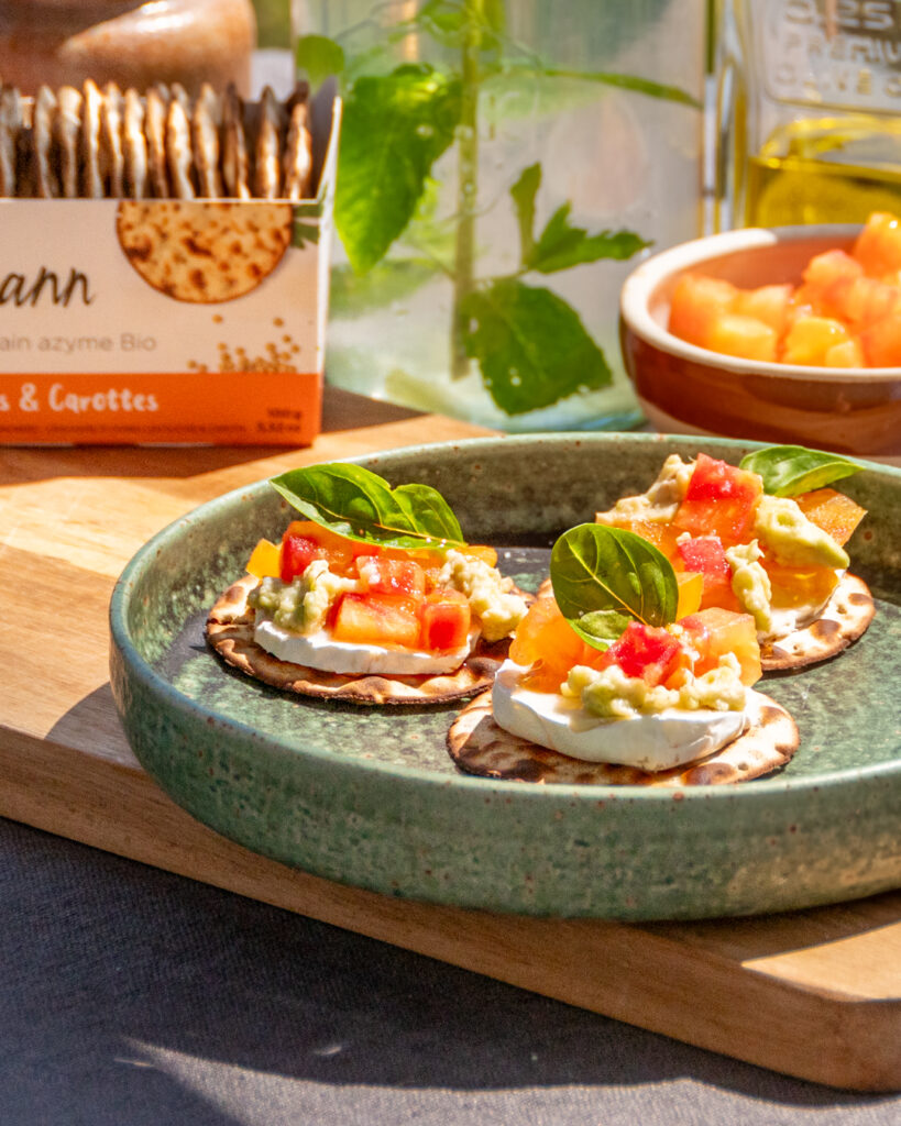 Tartines de pain azyme Heumann aux légumes frais, chèvre et guacamole servies avec une eau citron-menthe